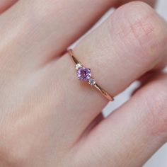 a woman's hand with a gold ring and two pink sapphires on it