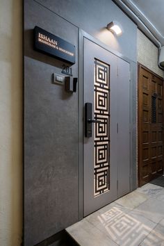 an entrance to a building with metal doors and decorative designs on the front door, next to a bench