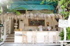 an outdoor bar with stools and plants growing on the outside wall, in front of a restaurant