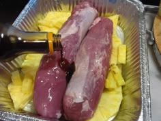 two raw sausages are in a pan with pineapple slices