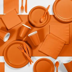 an orange table setting with utensils and napkins