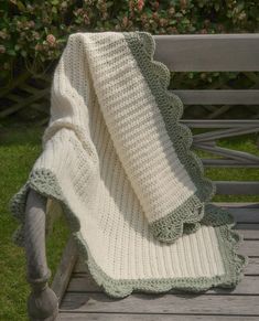 a crocheted blanket sitting on top of a wooden bench