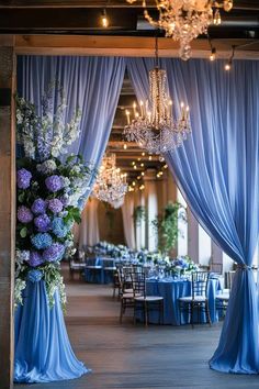 a room with blue drapes, chandeliers and tables set up for an event