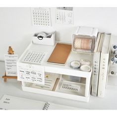 a white desk topped with lots of books and office supplies next to a calculator