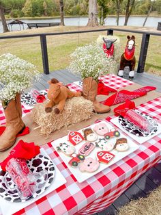 an outdoor picnic table set up with cowboy themed food and decorations, including cowgirl boots