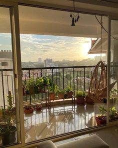 the sun is setting on an apartment balcony with potted plants and hanging hammock