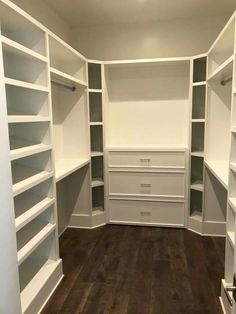 an empty walk in closet with white shelving and wood flooring on the side