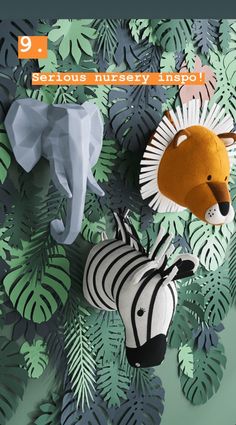 two stuffed animals are hanging on the wall next to some green leaves and palm fronds