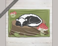 a black and white cow laying on top of a green blanket with mushrooms in the background