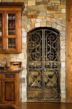 a kitchen with wooden cabinets and an iron gate in the center, surrounded by stone walls