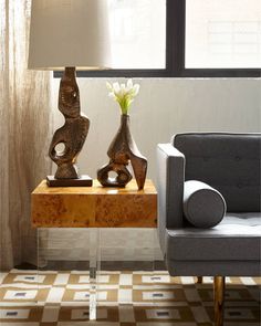 two vases with flowers sit on a table in front of a couch and window