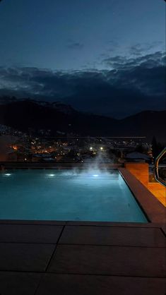 an empty swimming pool at night with the lights on and water spouting from it