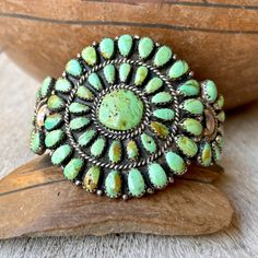 This vintage cuff bracelet is not just striking for the medallion style design done in a petit point setting but also for the green color of the turquoise. The piece was made circa 1970s by Navajo silversmith Juliana Williams and her sister-in-law Martha Smiley. The turquoise color has quite a bit of warm, caramel-colored matrix throughout. It is not a heavy piece, yet it displays impressive artistry, with each piece of turquoise hand-cut to fit into the small sawtooth bezels. Juliana Williams i Green Turquoise Jewelry, Native Necklace, Turquoise Stone Jewelry, Vintage Cuff Bracelet, Zuni Jewelry, Native American Earrings, Native American Rings, American Indian Jewelry, Native American Turquoise