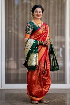 a woman in an orange and green sari is standing by a glass door with her hands on her hips