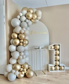 the balloon arch is decorated with gold and white balloons