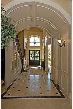 an archway leads to the front door of a house with tile flooring and walls