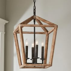 a wooden lantern hanging from the ceiling with three candles in it and one light on each side