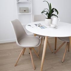 a white table with two chairs and a potted plant