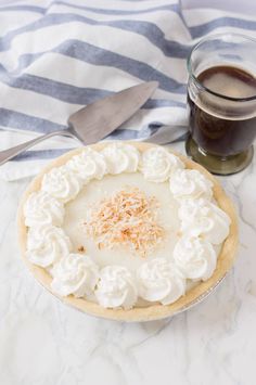 a pie sitting on top of a table next to a cup of coffee and spoon