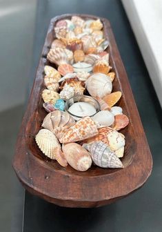 a wooden boat filled with seashells on top of a table