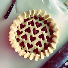 a pie with hearts cut out of it sitting on a cutting board next to a knife