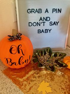 two pumpkins sitting on top of a table next to a sign that says grab a pin and don't say baby