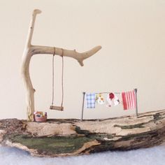 a driftwood tree branch with a toy swing and flag hanging from it's side