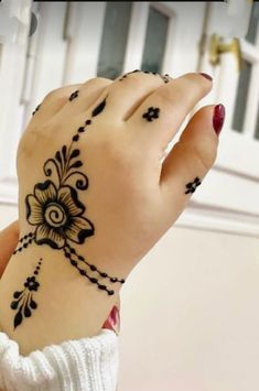 a woman's hand with black henna on her left wrist and the other hand holding