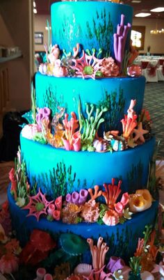 a three tiered cake decorated with sea life and corals on a table in a banquet room