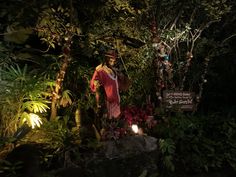 a man is standing in the middle of a garden at night with lights on his head