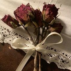 dried roses are tied with ribbon and placed on a piece of fabric next to a lace doily