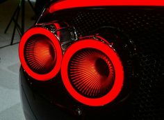 the front end of a sports car with red lights on it's taillights