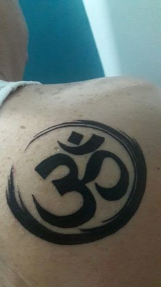 the back of a person with a tattoo on their shoulder and an om shant