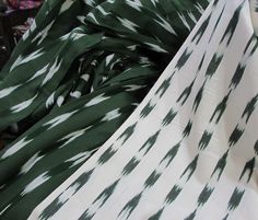 the fabric is green and white with black spots on it's edges, as well as an abstract pattern