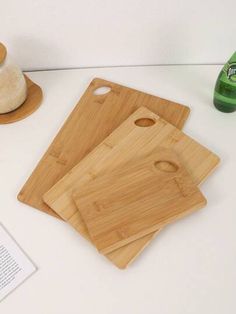 three wooden cutting boards sitting on top of a table next to a bottle of beer