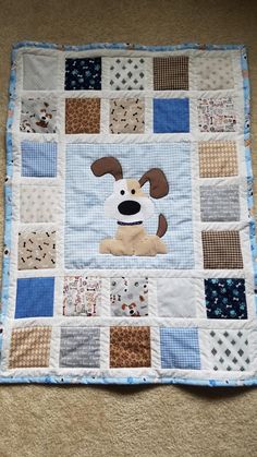 the dog is sitting on the blue and white patchwork quilted baby bedding