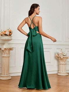 a woman in a long green dress with a bow on the back, looking down