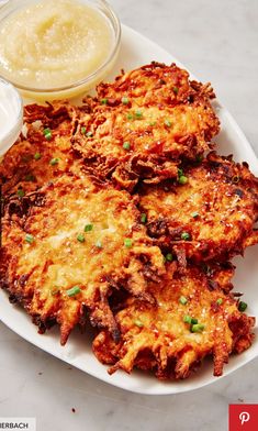 some fried food on a white plate next to a small bowl of mayonnaise