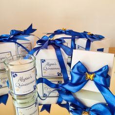 a candle and some cards with blue ribbons on them sitting next to each other in front of a box