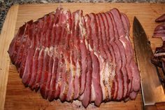 sliced meat sitting on top of a cutting board next to a knife