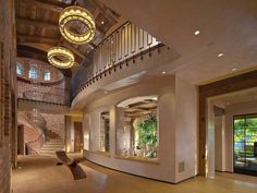 the inside of a large house with stairs and chandeliers hanging from the ceiling