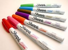 six sharpie pens lined up in a row on a white surface with different colors