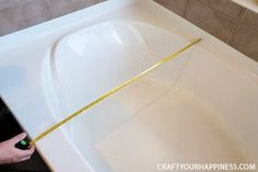 a person measuring the width of a bathtub with a tape on it's edge