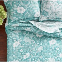 a close up of a bed with flowers on the comforter and pillowcases