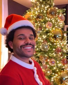 a man wearing a santa hat in front of a christmas tree