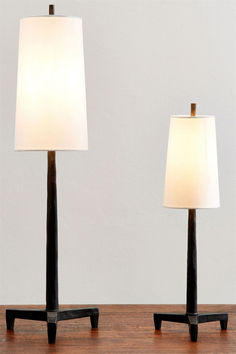 two lamps sitting on top of a wooden table next to each other, one with a white lamp shade