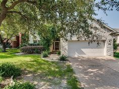 a house with a driveway in front of it and trees on the other side of the house