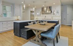 a kitchen with a table and chairs in the center, lights hanging from the ceiling