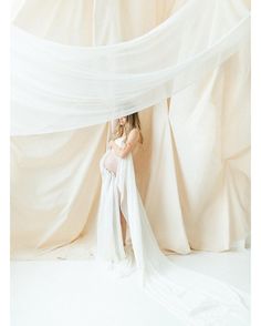 a woman in a white dress is posing for the camera with her long veil draped over her head