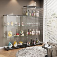 a glass display case filled with lots of bottles and glasses on top of a wooden floor